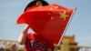 一名站在北京天安门广场的小男孩身穿美国T恤手拿中国国旗。（2019年5月7日）