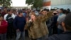Mirna Contreras, de Honduras, canta mientras otros migrantes esperan en la cola para cenar en un albergue donde viven los miembros de la caravana de migrantes, en Tijuana, México, el lunes 26 de noviembre de 2018.