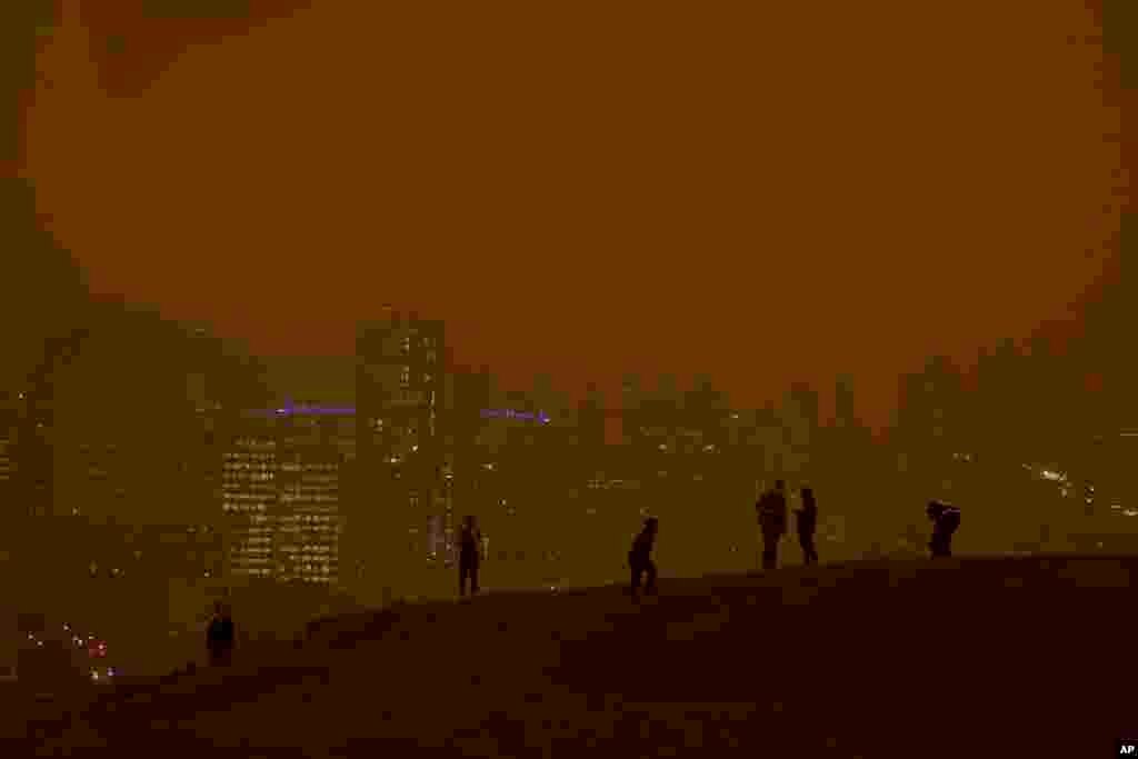 People look at the skyline obscured by wildfire smoke during daytime from Kite Hill Open Space in San Francisco, California.