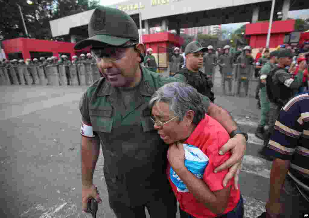 Một sĩ quan quân đội an ủi một người ủng hộ Tổng thống Venezuela Hugo Chavez bên ngoài bệnh viện quân đội ở Caracas, Venezuela, ngày 5/3/2013.